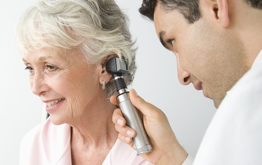 hearing specialist using a specialized tool to examine patients inner ear