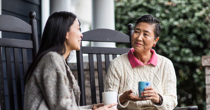 Two women talking while holding coffee cups